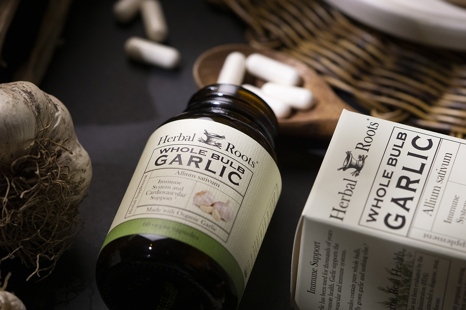Close up of Herbal Roots garlic bottle on its side with capsules spilling out onto a wooden spoon.
