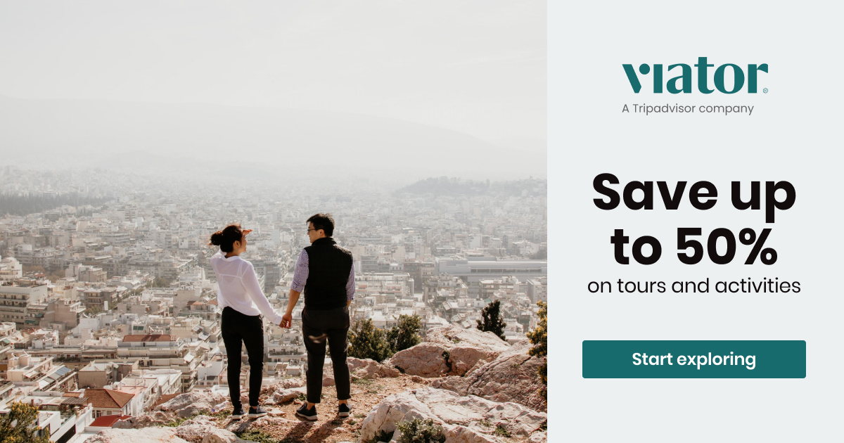 a man and woman holding hands on a mountain overlooking a city