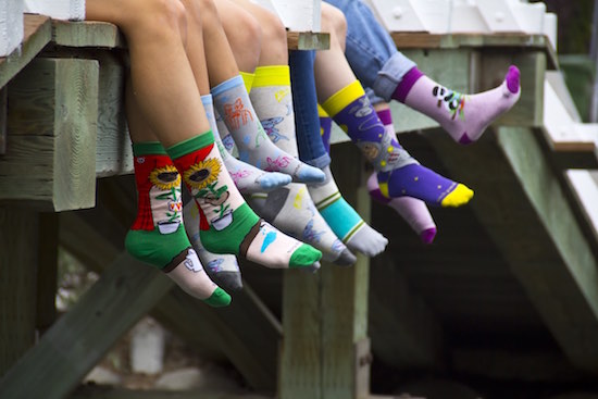 dock with kids legs hanging down all wearing colorful sock designs